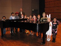 Students surround piano in concert hall